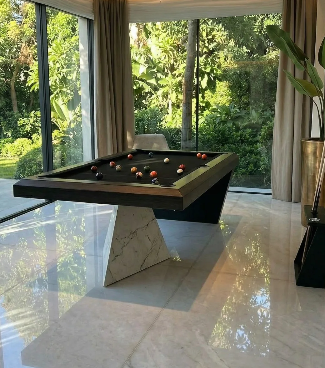 Table de billard Vertice finition sombre, vue de trois quarts devant une baie vitrée